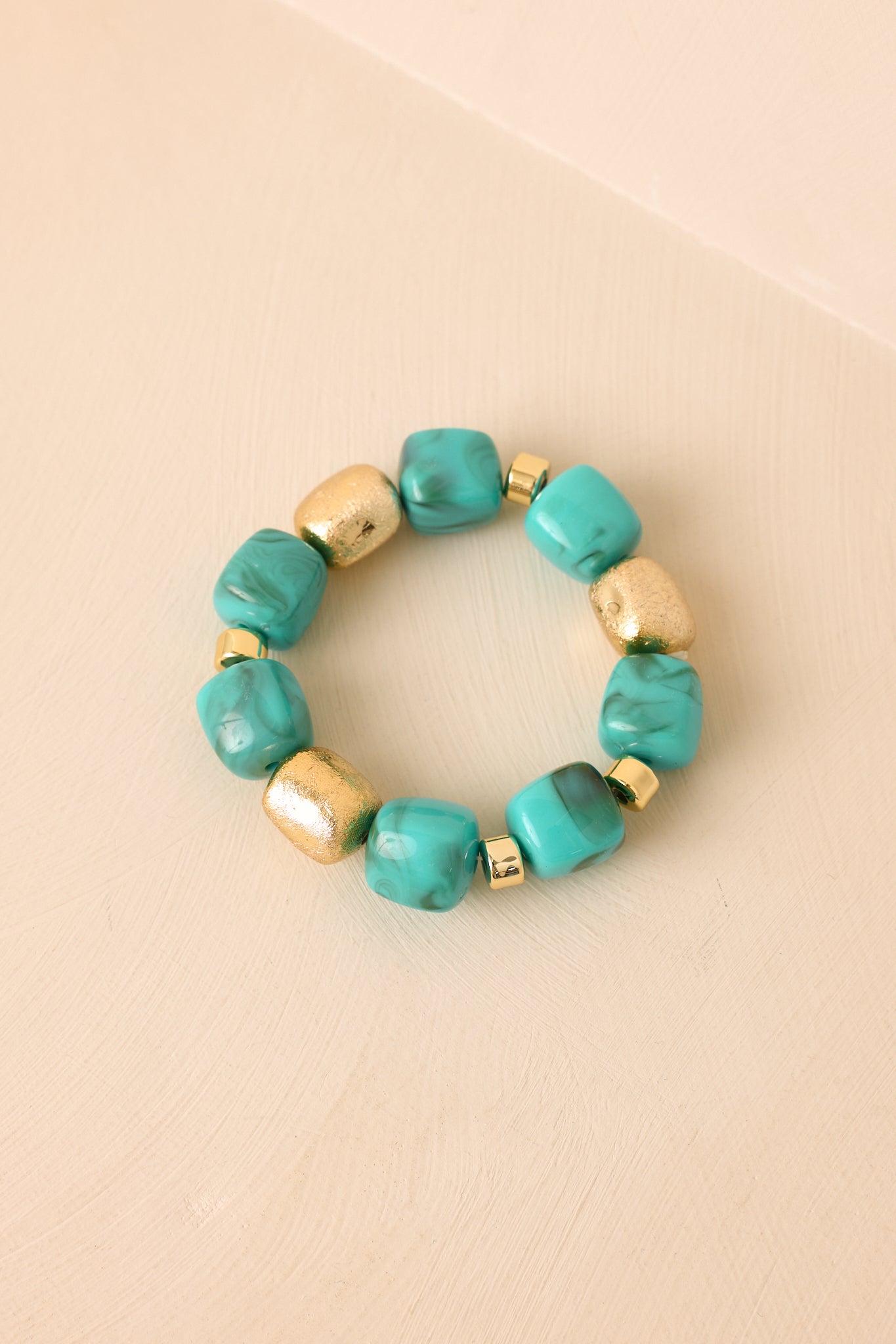Bold bead bracelet showcasing turquoise-inspired tones, gold accent pieces, and a lightweight stretch silhouette.