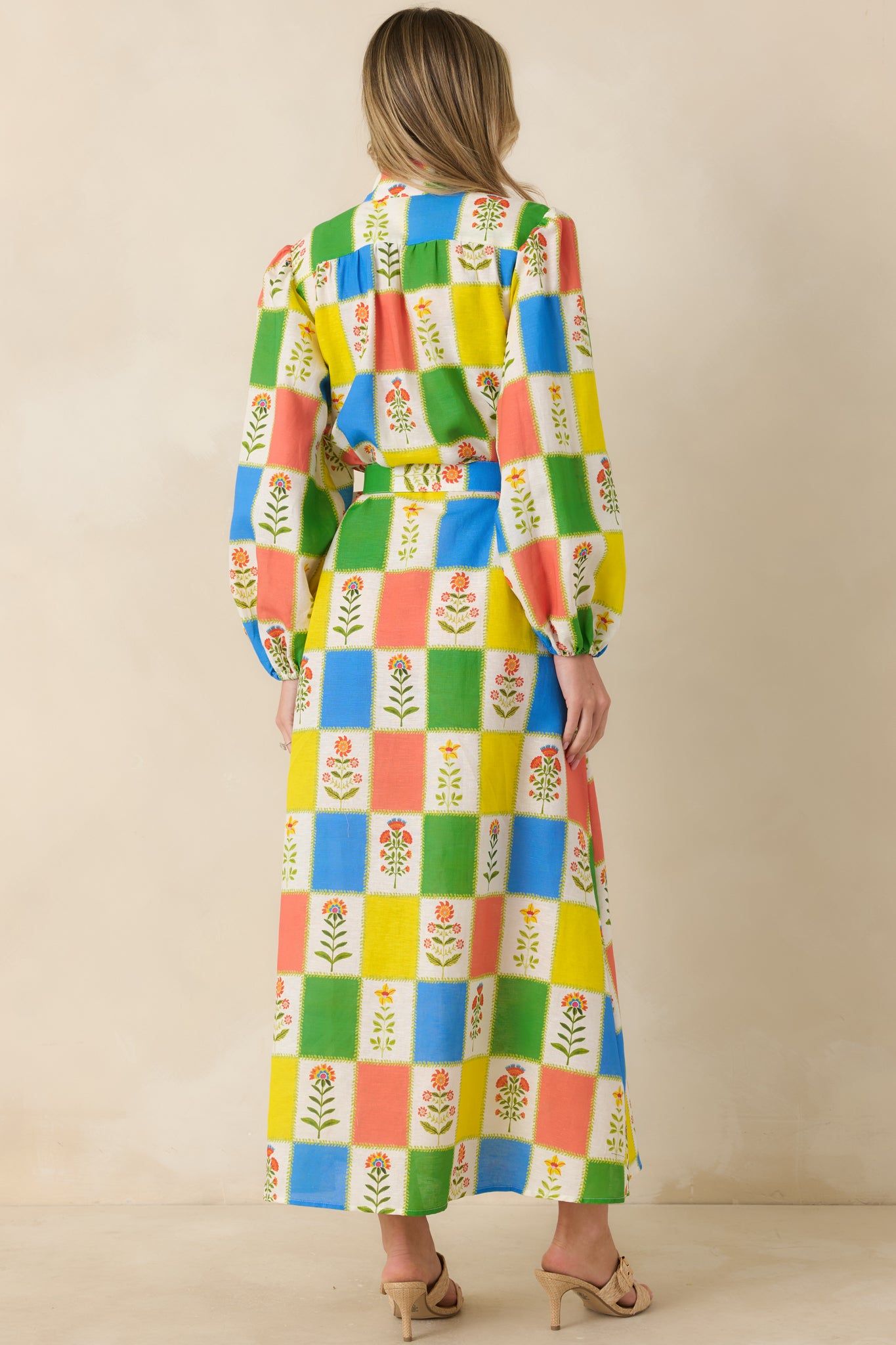 Rear view of the maxi dress showing the flowing full-length skirt, long sleeves with soft cuff volume, and smooth, structured drape through the back.