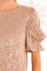Close up view of this top that features a round neckline, a keyhole opening on the back, puff sleeves with elastic cuffs, and sequins throughout. 