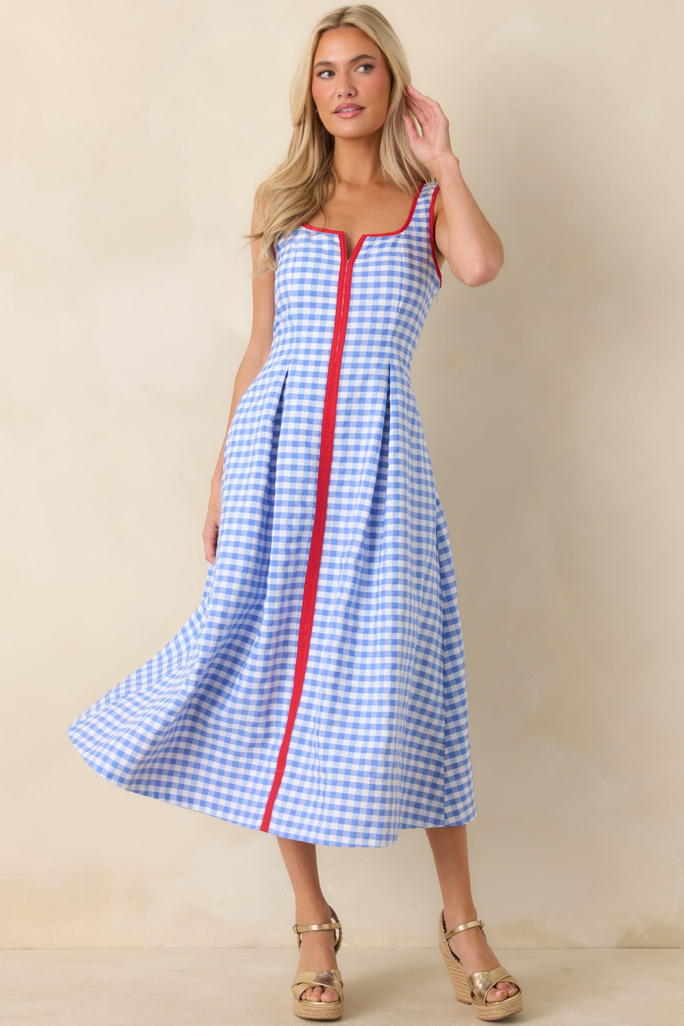 Blue and white gingham midi dress featuring a sleeveless silhouette, notched neckline, and red contrast trim.