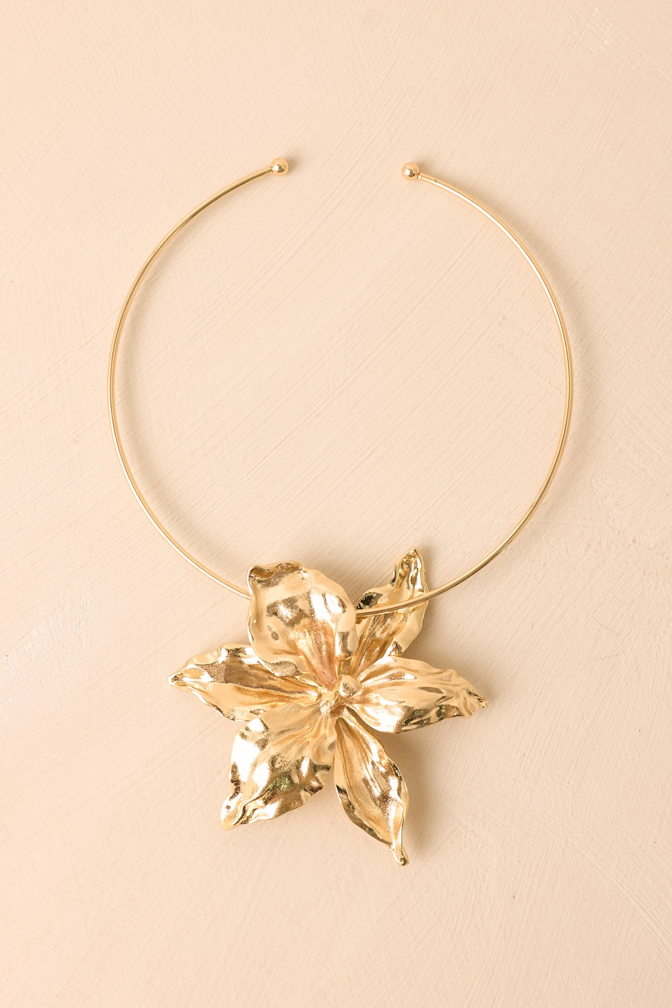 Statement gold necklace featuring a dimensional sculpted flower pendant and elegant structured silhouette.