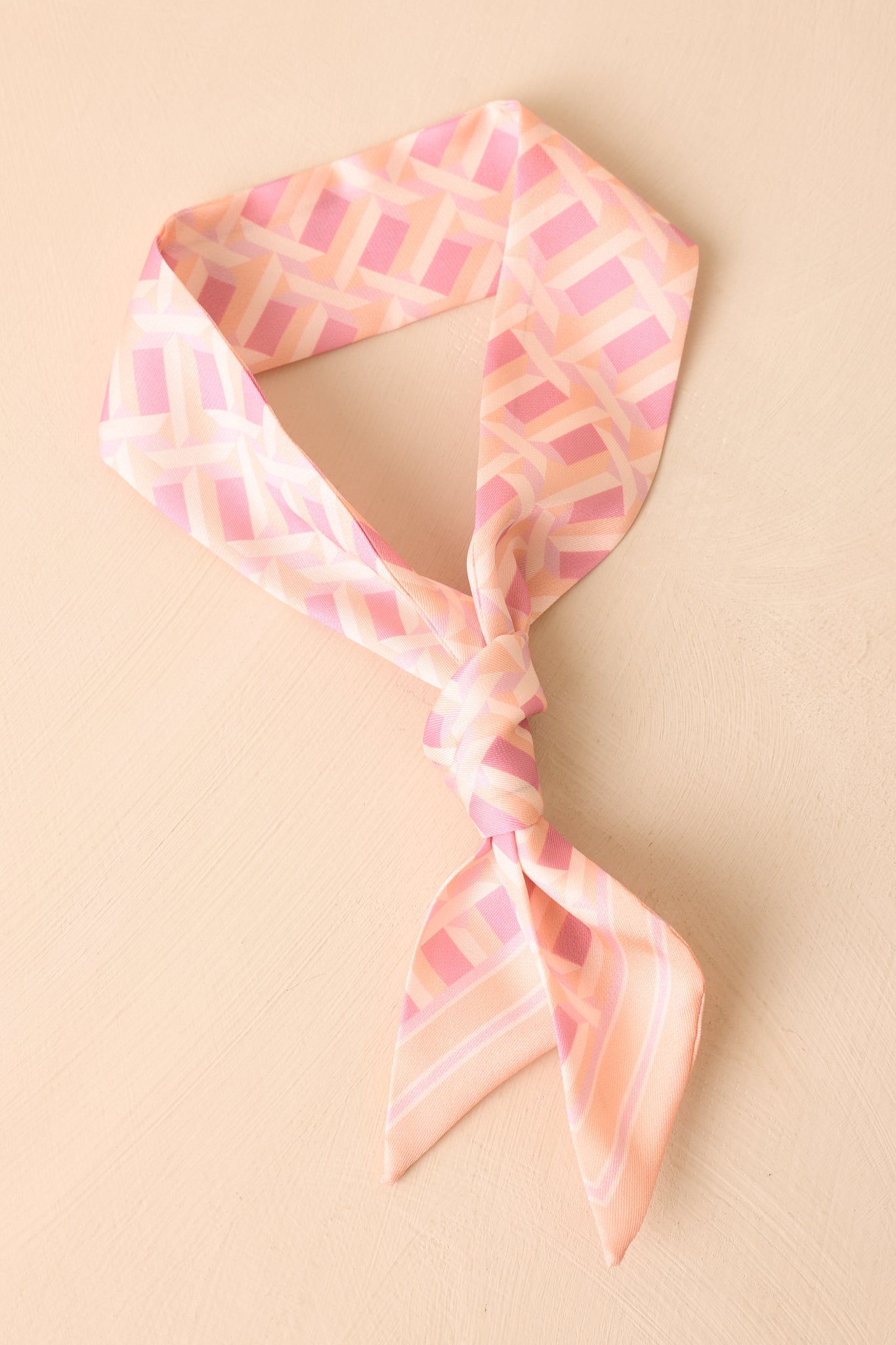 Slim pink geometric print scarf with blush, peach, and ivory shading. 