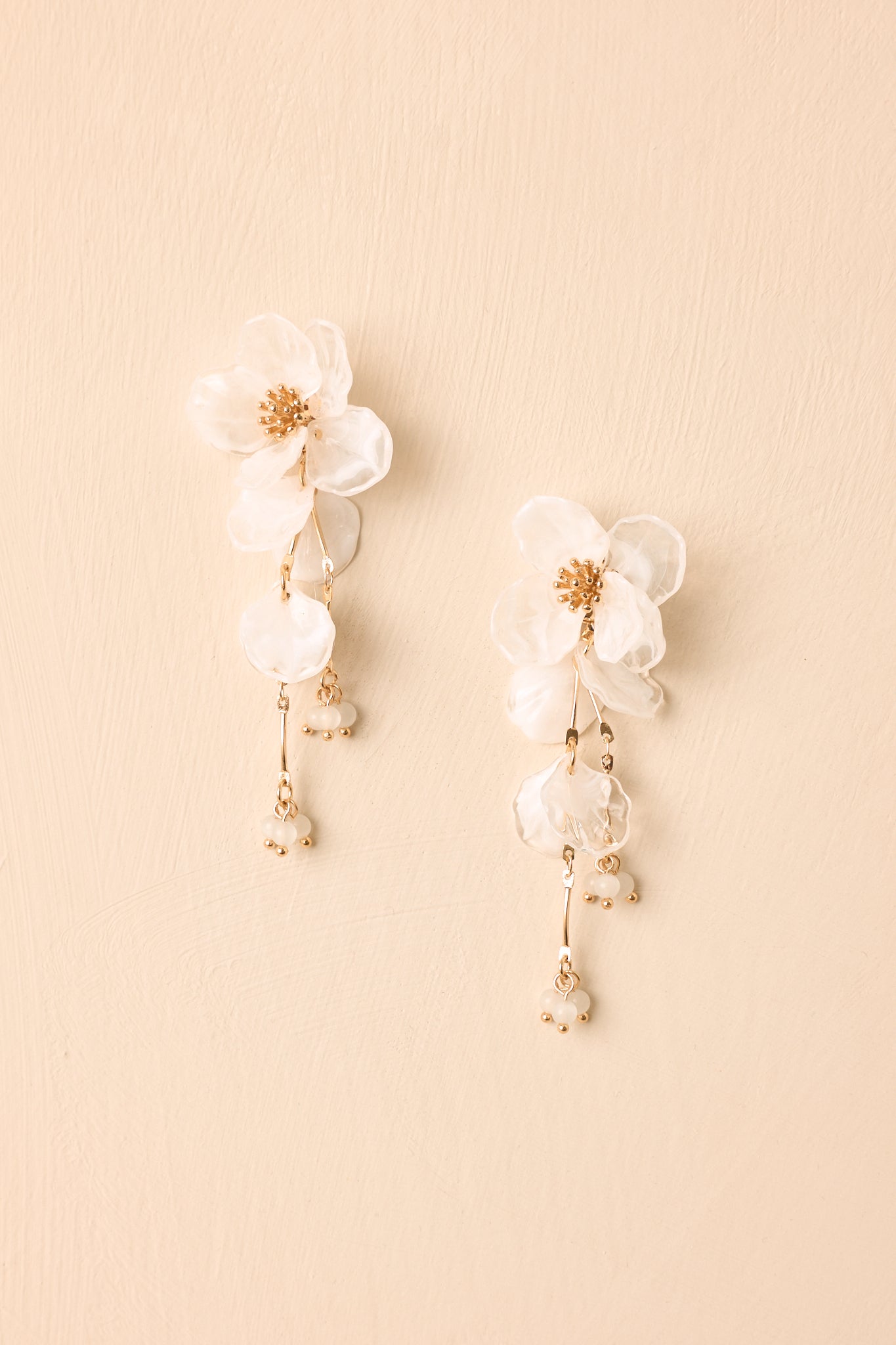 White and gold earrings showcasing marbled translucent petals, delicate bead accents, and a lightweight floral silhouette.