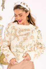 This ivory sweater features a ribbed crew neckline, hemline slits, and eccentric sequin designing.