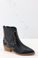 Outer-side view of these ankle boots that feature a pointed toe, a side zipper closure, a stretchy side panel, embroidered detailing, and a stacked heel.