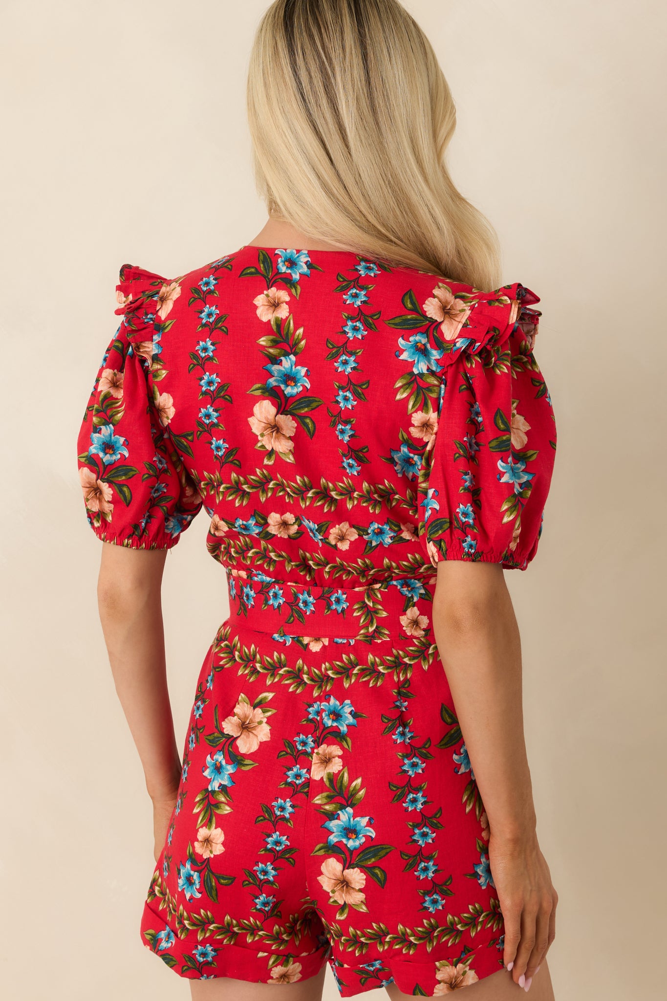Rear view of the red multi floral romper with puff sleeves, fitted waist, and smooth linen blend finish.