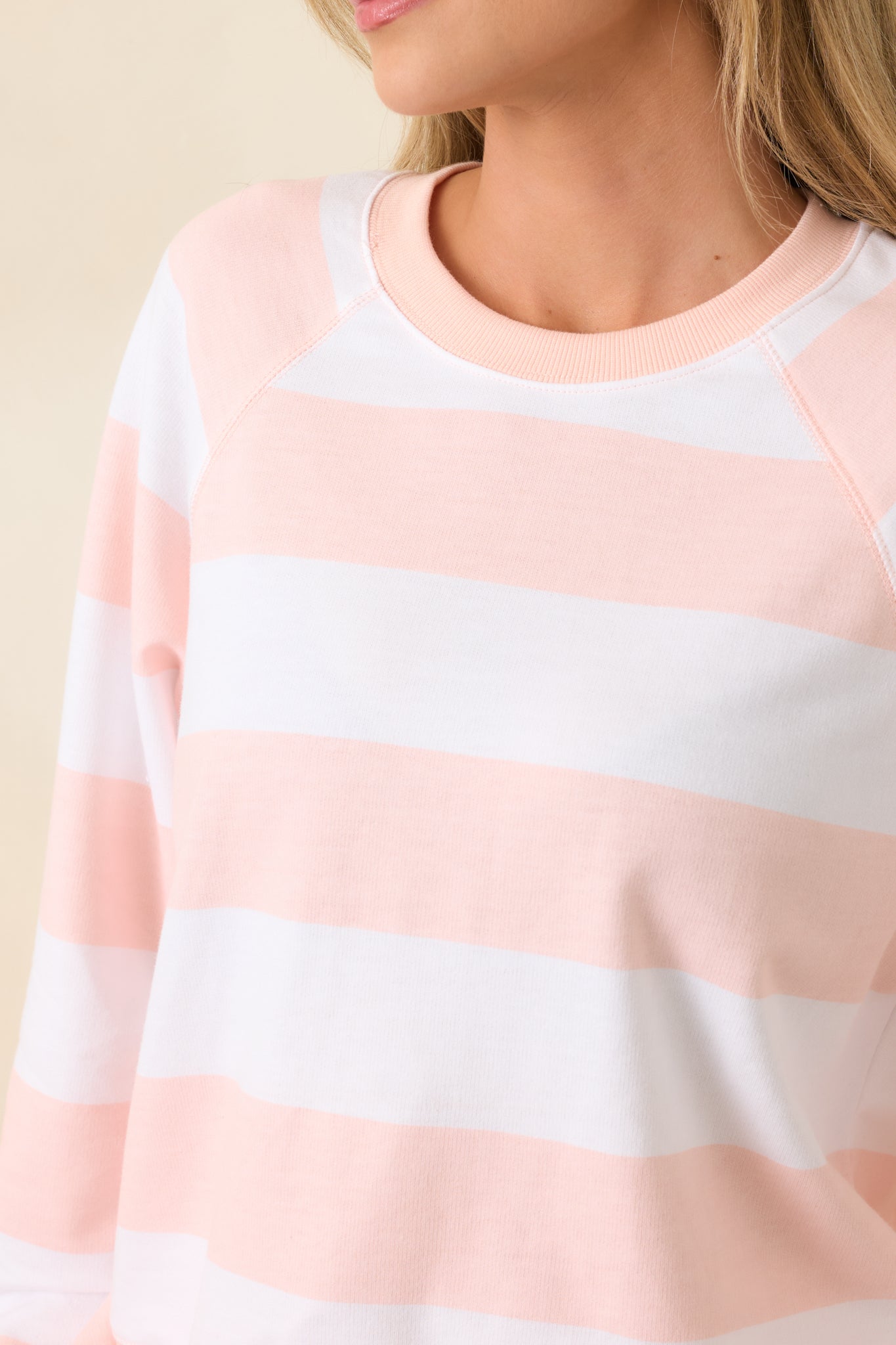 Close-up of sweatshirt showing cream and blush stripe pattern on soft cotton blend fabric.