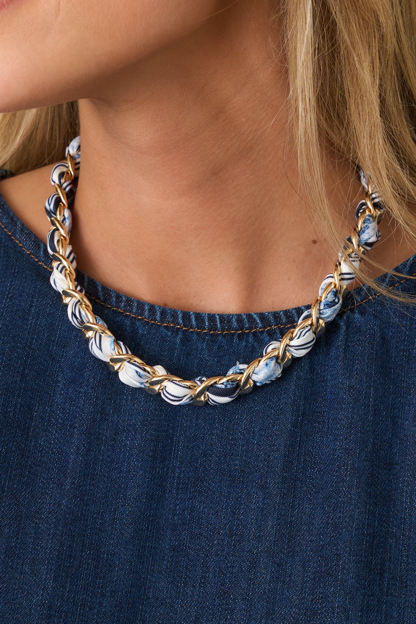 Close-up detail of necklace showing polished gold links, woven blue fabric, and secure clasp closure.