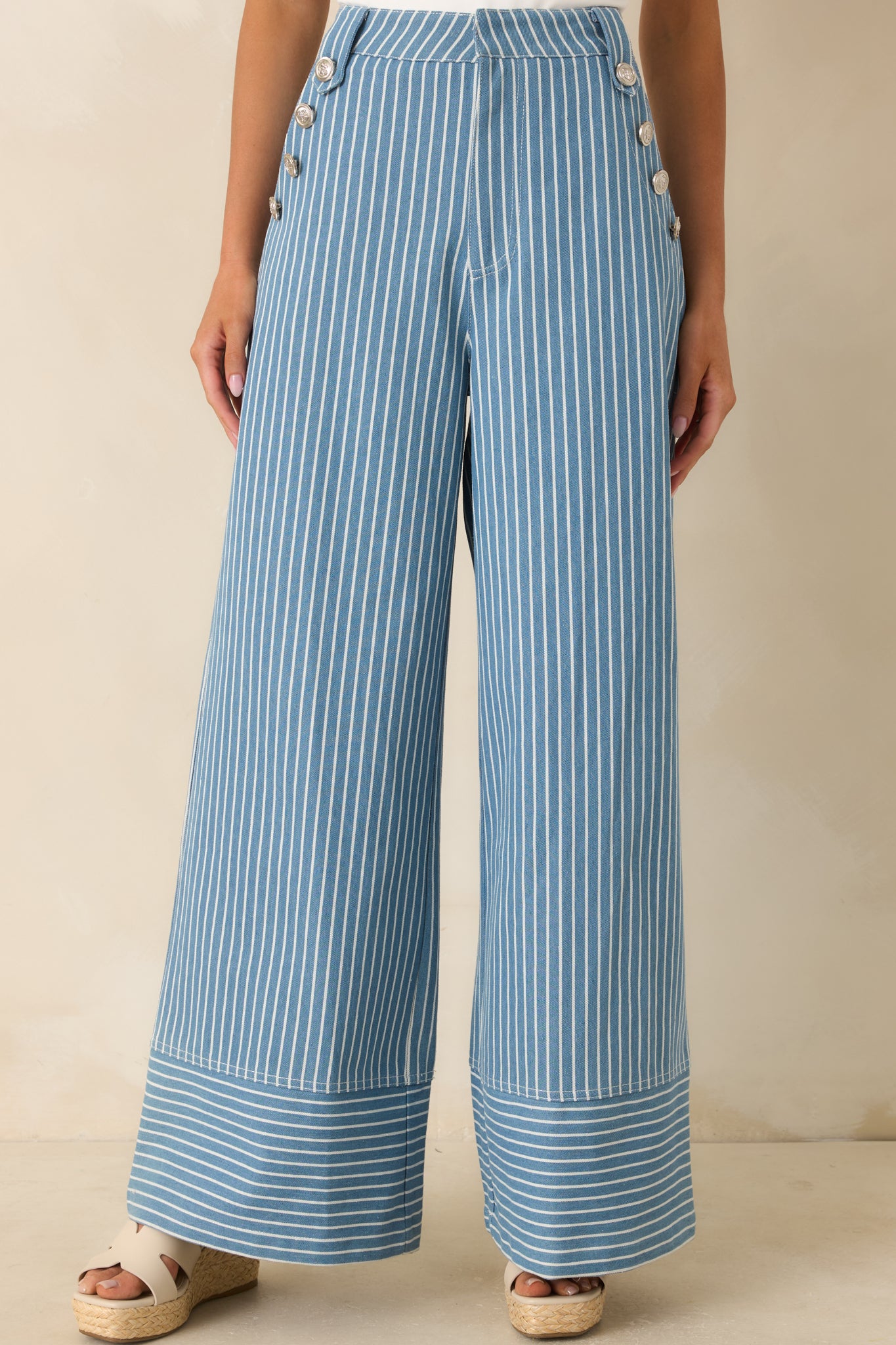 Close view of blue striped pants highlighting sailor-inspired silver button detailing at the waistband.