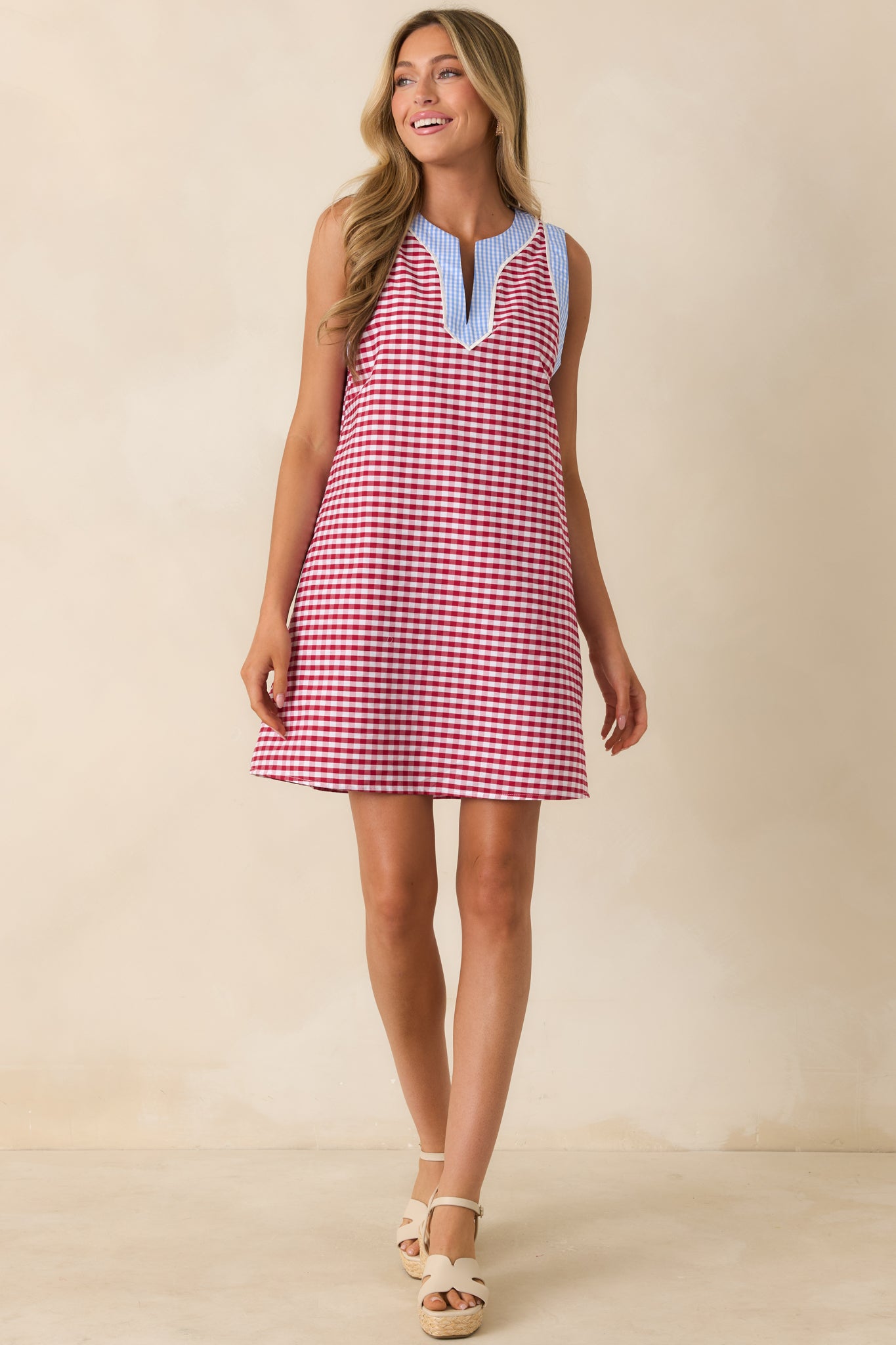 Sleeveless gingham mini dress showcasing a split neckline with light blue contrast detailing and a relaxed breathable cotton fit.