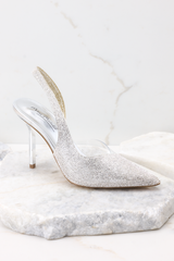 Side view of these heels that feature a pointed toe, rhinestone embellishments, a clear strap on the inside, and a non-adjustable back strap.