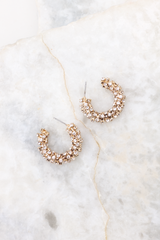 Overhead marble shot of earrings that feature rhinestones all over, an open hoop design, and secure post-back fastenings.