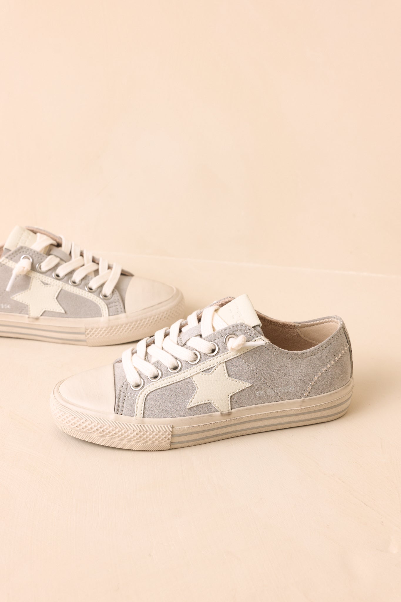 Dusty blue suede sneakers with breathable perforated detailing, tonal suede overlays, contrasting woven laces, and a durable rubber sole viewed from a different angle.