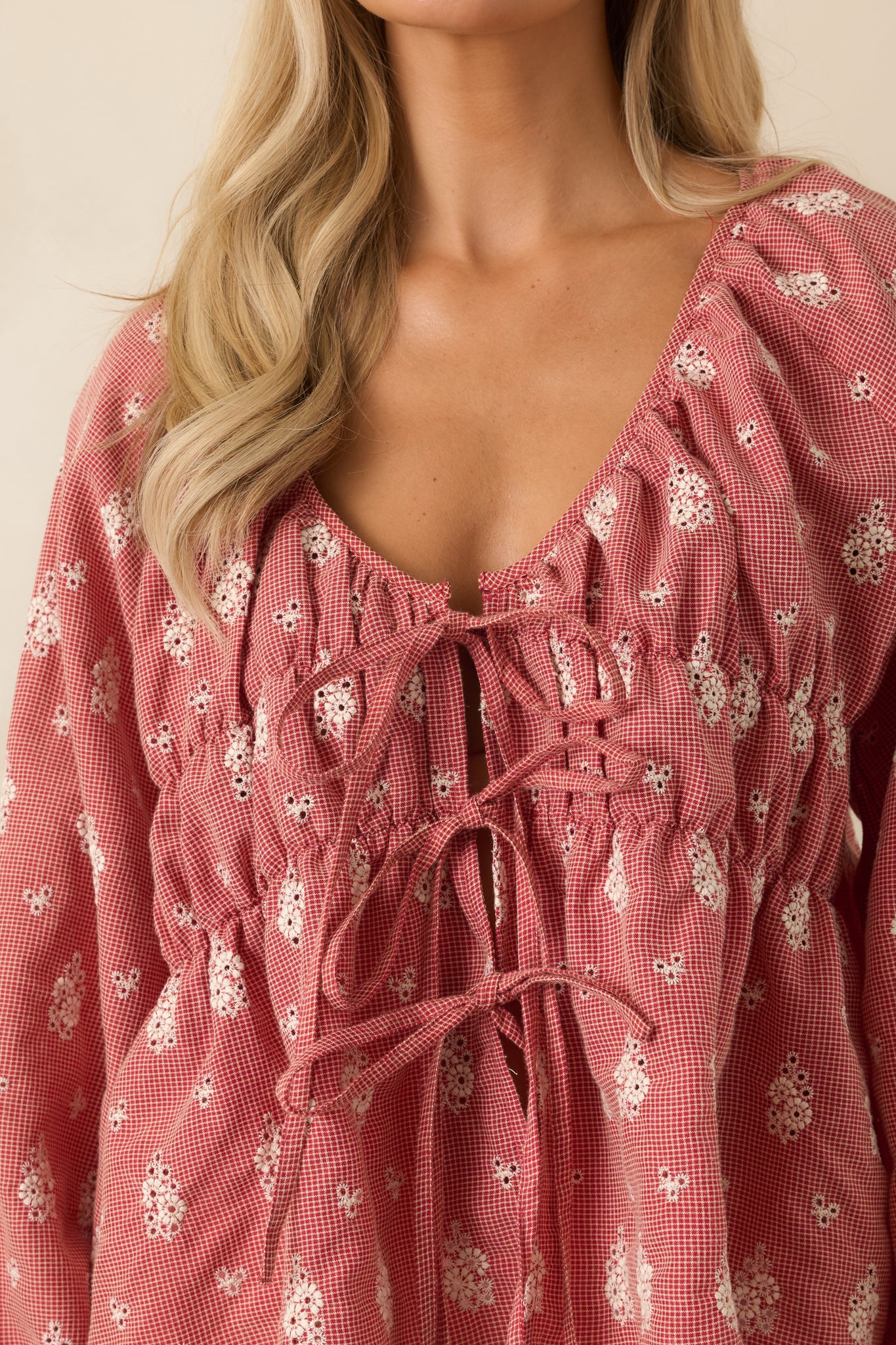 Close-up of red floral blouse highlighting self-tie front detailing, gathered neckline, and textured cotton fabric.