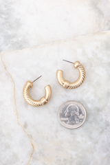 Top view of these earrings that feature a textured design, worn gold finish, and secure post-back fastenings.