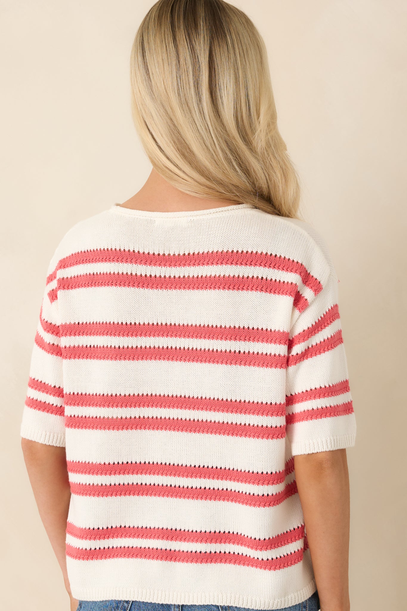 Rear view of ivory knit sweater with coral stripe pattern, and relaxed fit.