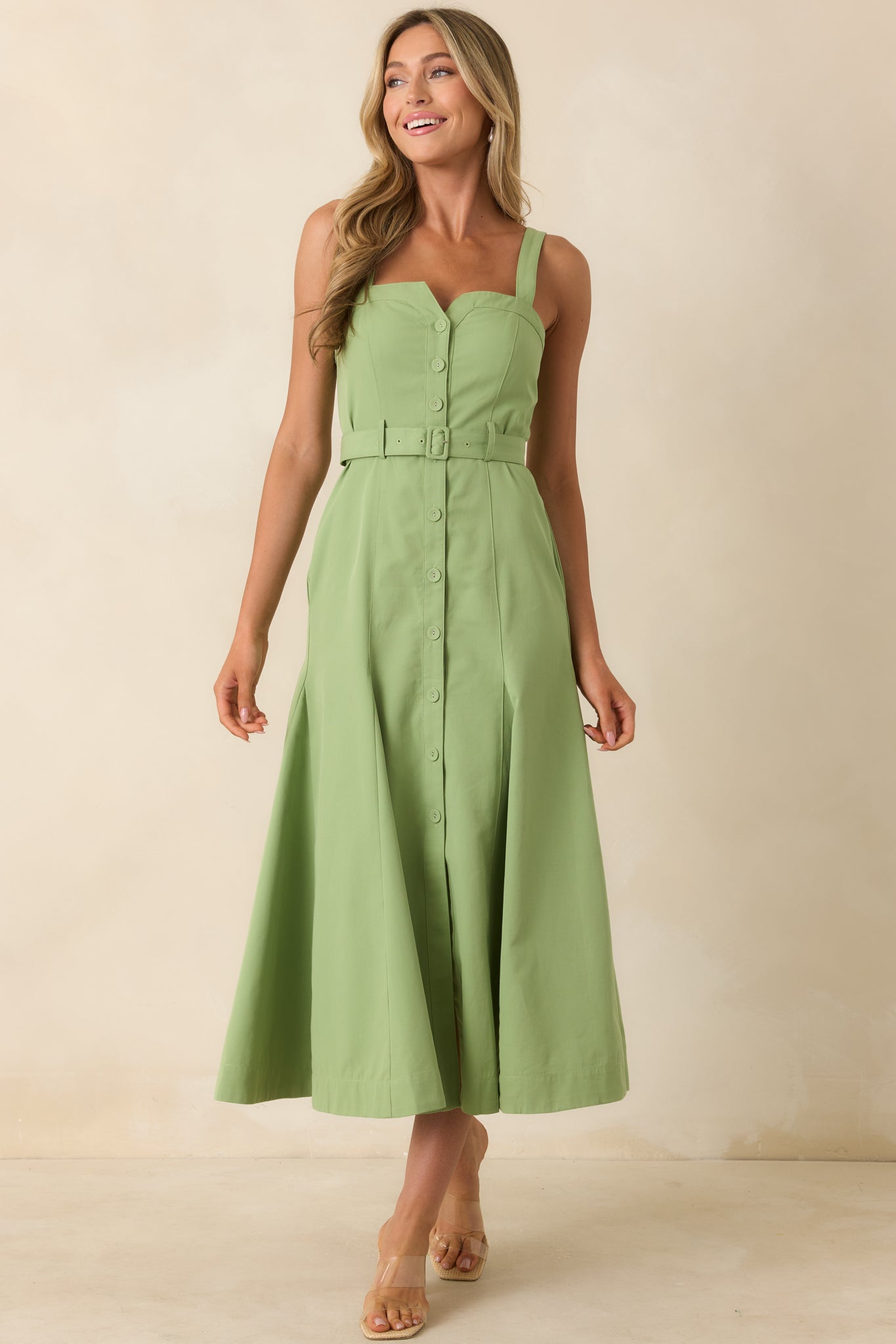 Green midi dress showcasing a functional button-front design, matching adjustable belt, and relaxed yet structured silhouette with side pockets.