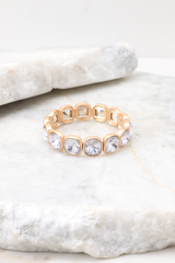 Detailed marble shot of bracelet that features gold hardware, rhinestone details, stretch band, and a slip-on style.