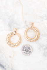 Size comparison of a quarter to gold, ribbed stud earrings attached to a ribbed hoop. Ribs increase in size around the hoop.
