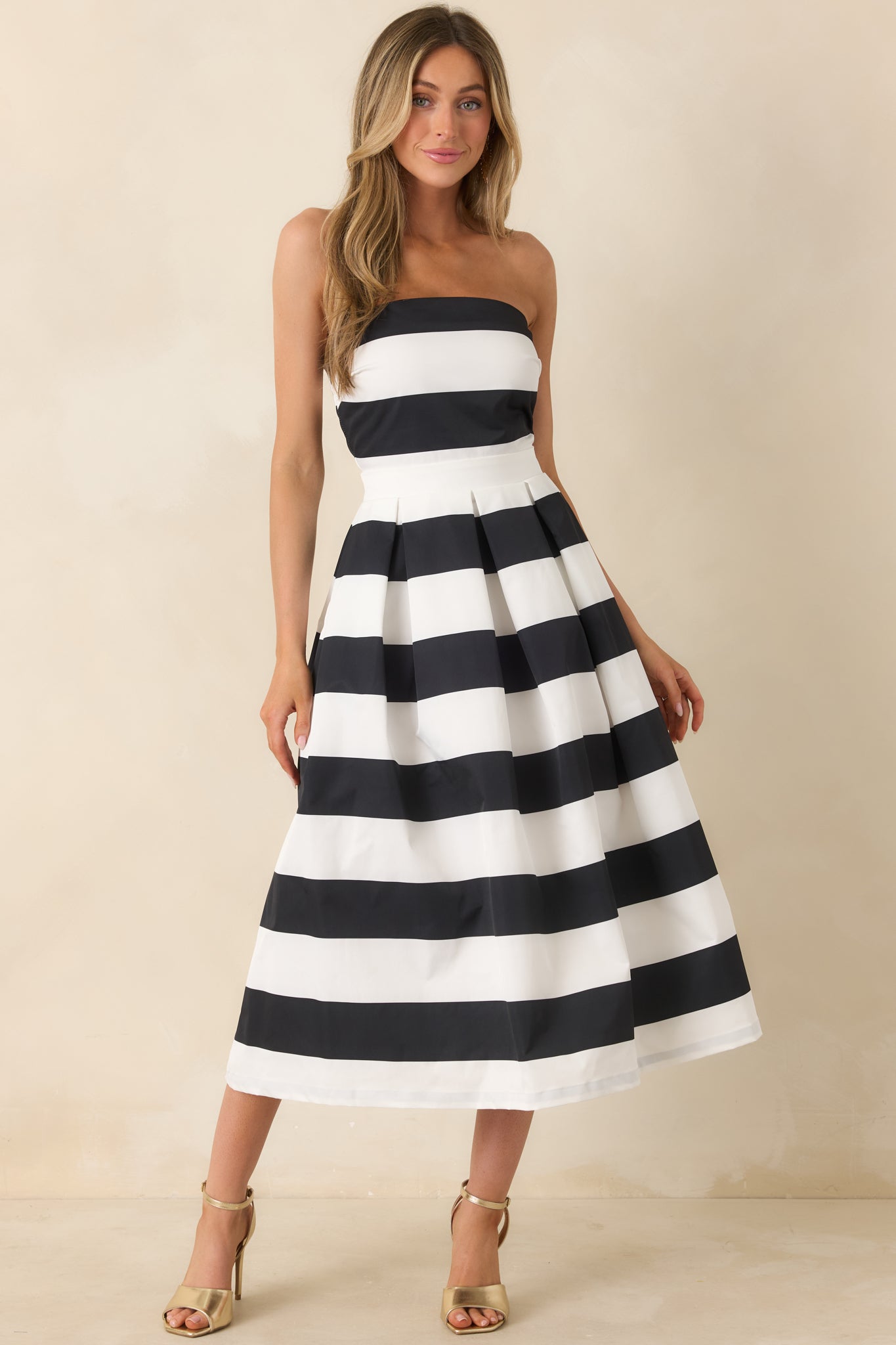 Woman wearing a black and white striped dress against a beige background.