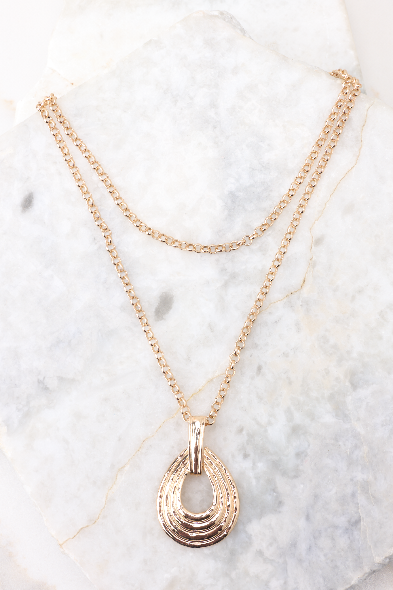 Close up view of this necklace that features a teardrop shaped pendant, a long chain that can be wrapped for a shorter length, and a lobster clasp. 