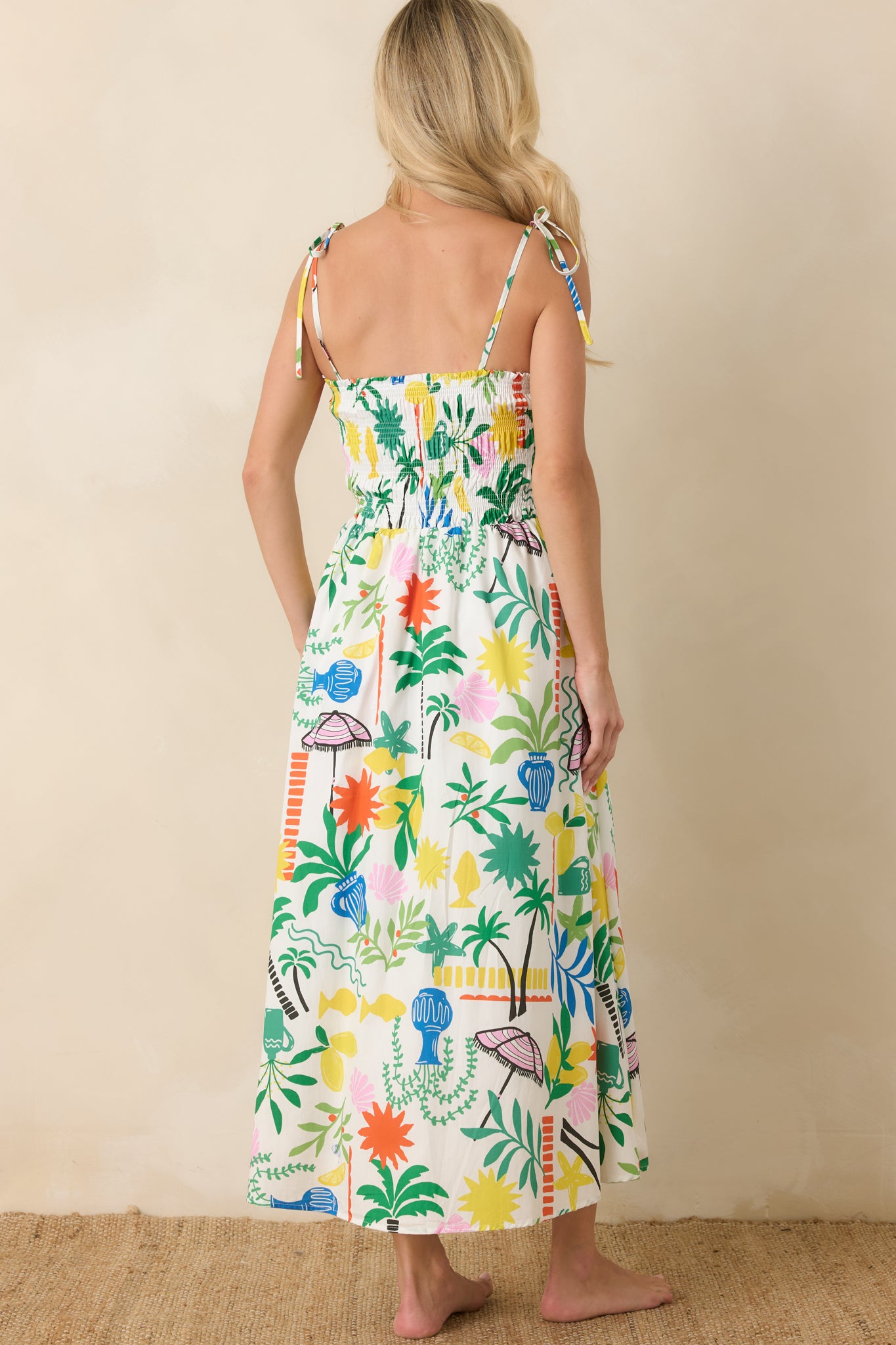 Rear view of the white multi cotton midi dress featuring adjustable tie straps, smocked back detailing, and a flowing printed skirt.
