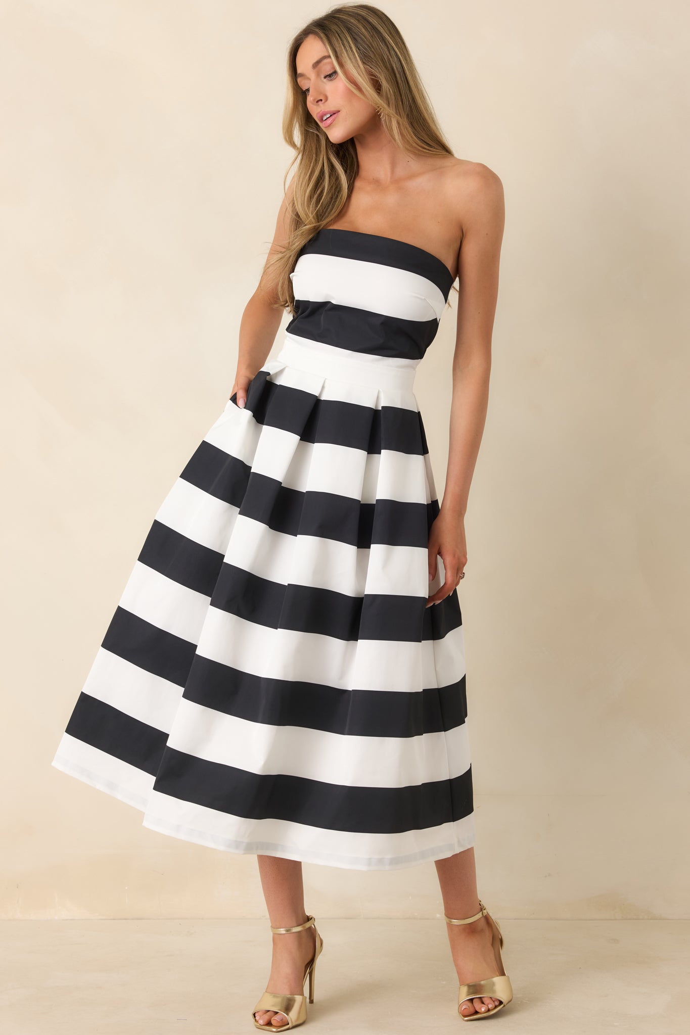 Front view of a dress featuring a strapless neckline, a thick waistband, functional hip pockets, and a timeless stripe pattern.