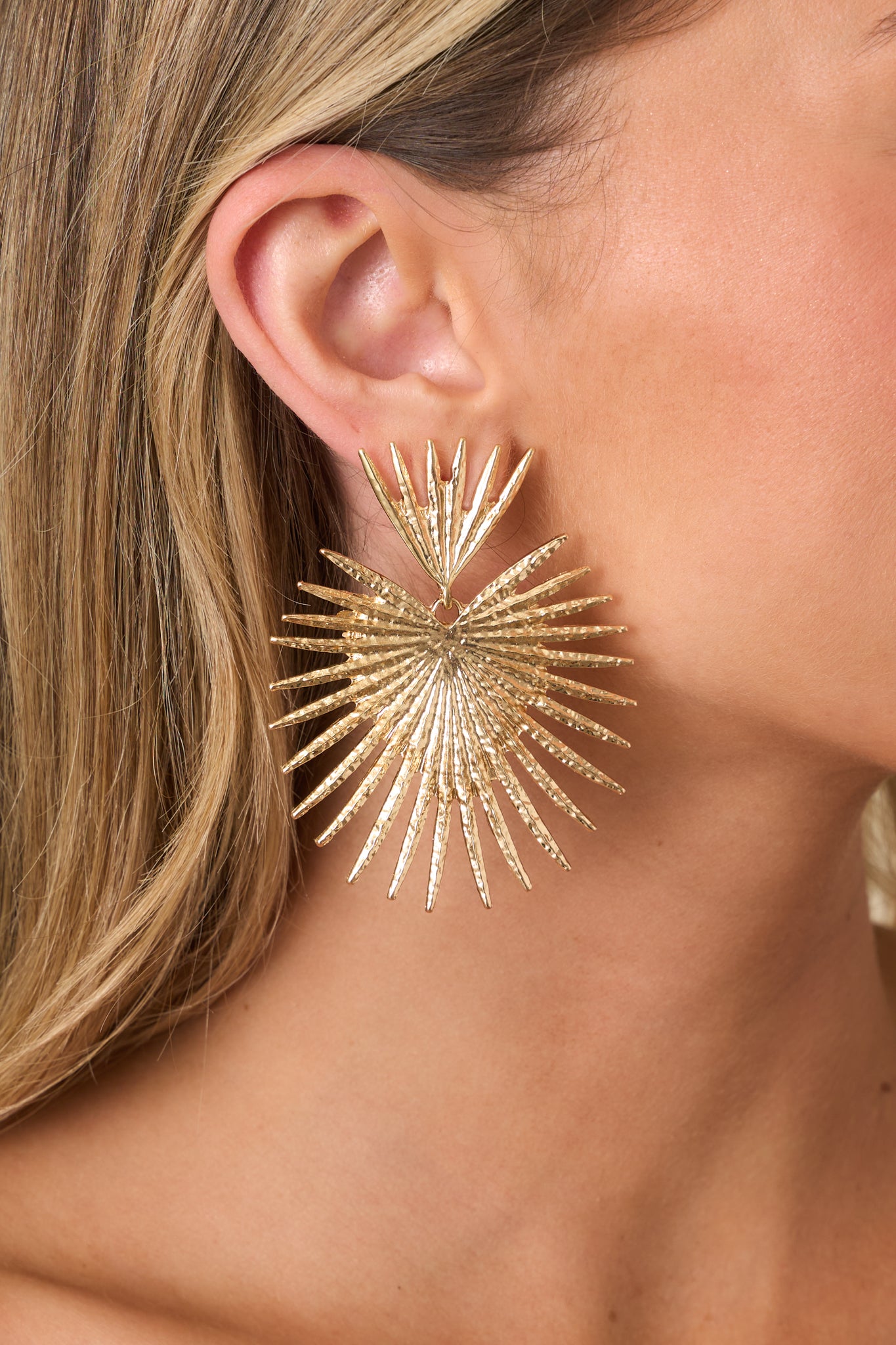 Close-up of gold earrings highlighting the intricate detailing, textured elements, and secure post backing.