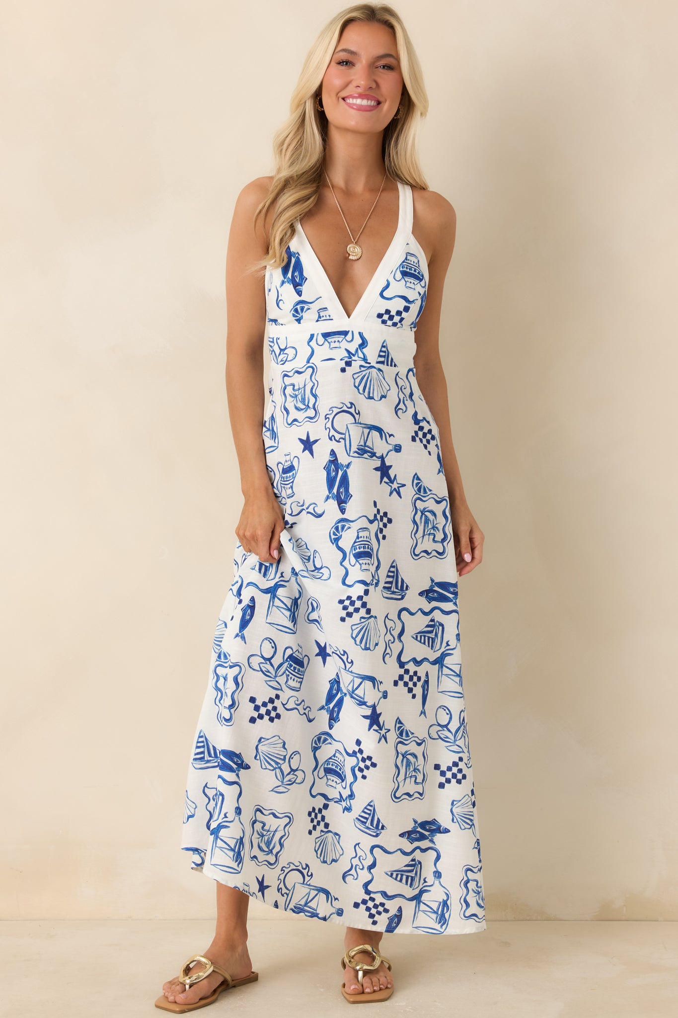 White midi dress with halter neckline and intricate blue coastal-inspired pattern.