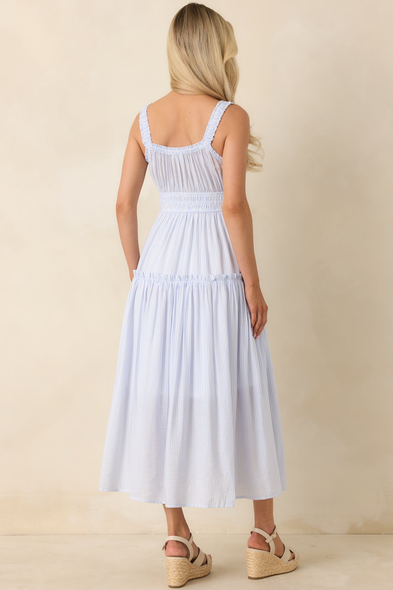 Rear view of pinstripe tiered dress with smocked waist and flowing silhouette.