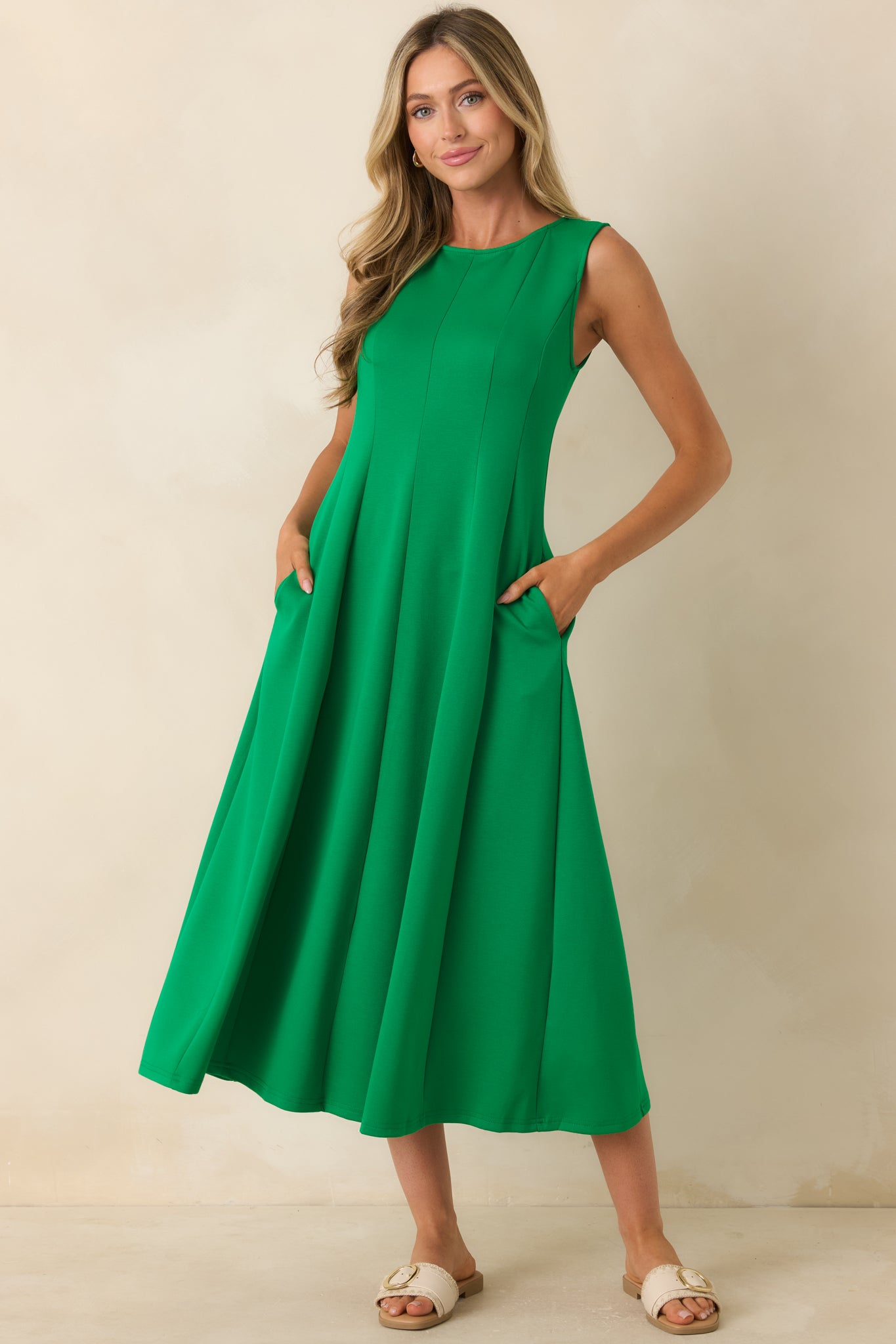 Sleeveless green midi dress showcasing seamed panel construction, hidden side pockets, and an easy pull-on fit.