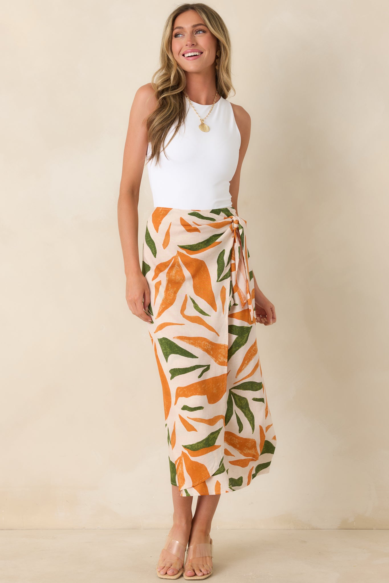 Orange and green tropical print midi skirt with high-waisted wrap design and flowing silhouette.