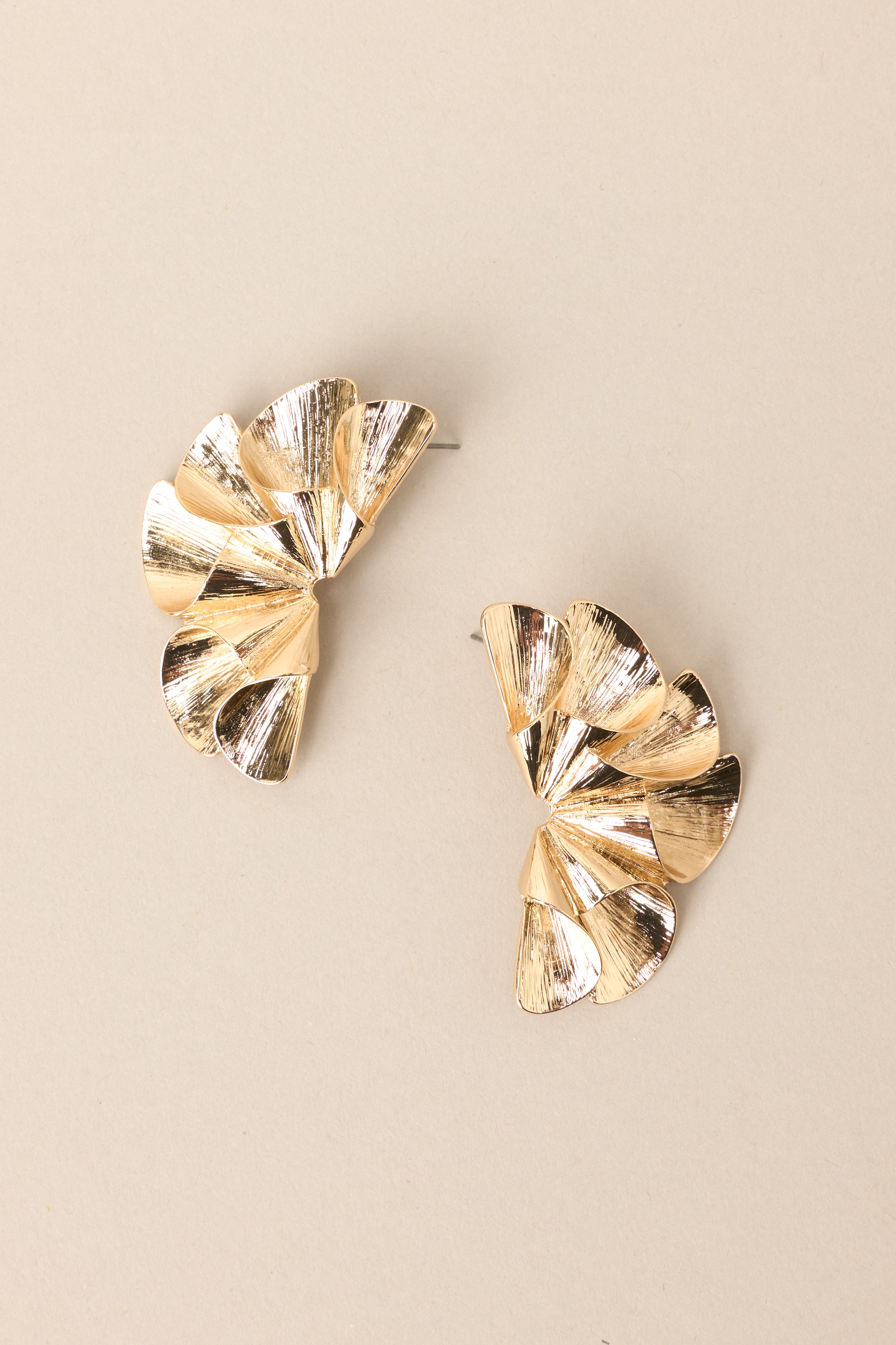 Top view of these earrings that feature gold hardware, a unique and abstract design, and secure post backings.