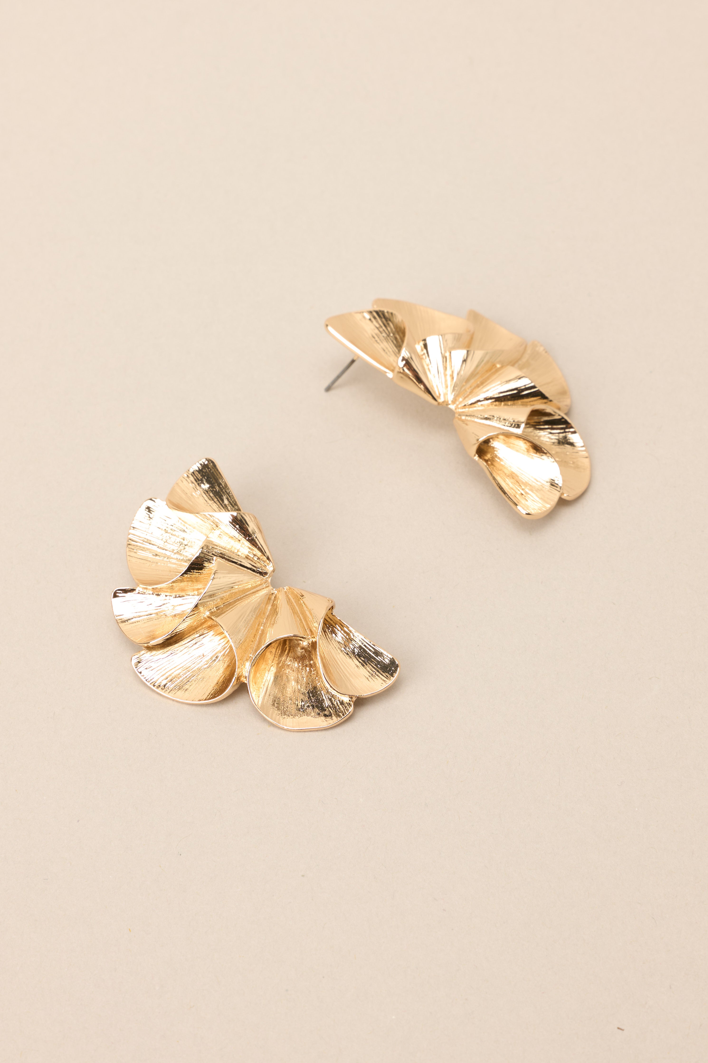 Side view of these earrings that feature gold hardware, a unique and abstract design, and secure post backings.