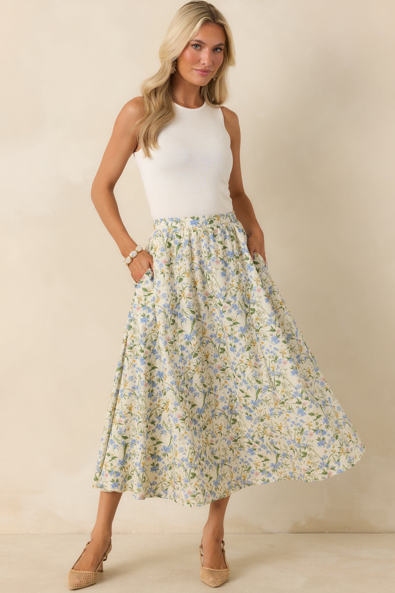 Green multi-colored cotton floral midi skirt featuring a high-rise gathered waistband, A-line silhouette, and soft green, yellow, and blue floral print.