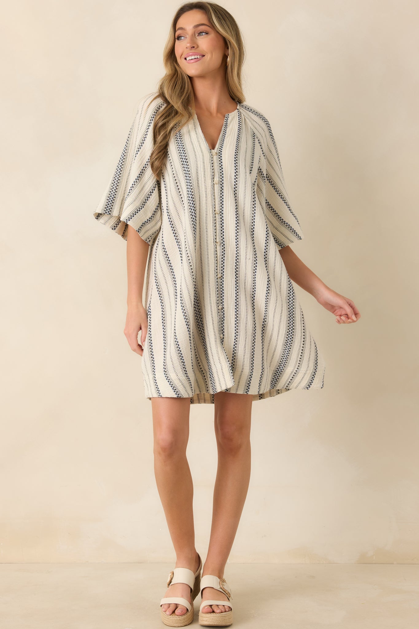 Relaxed cotton mini dress with split neck, vertical stripe pattern, and loose drape.