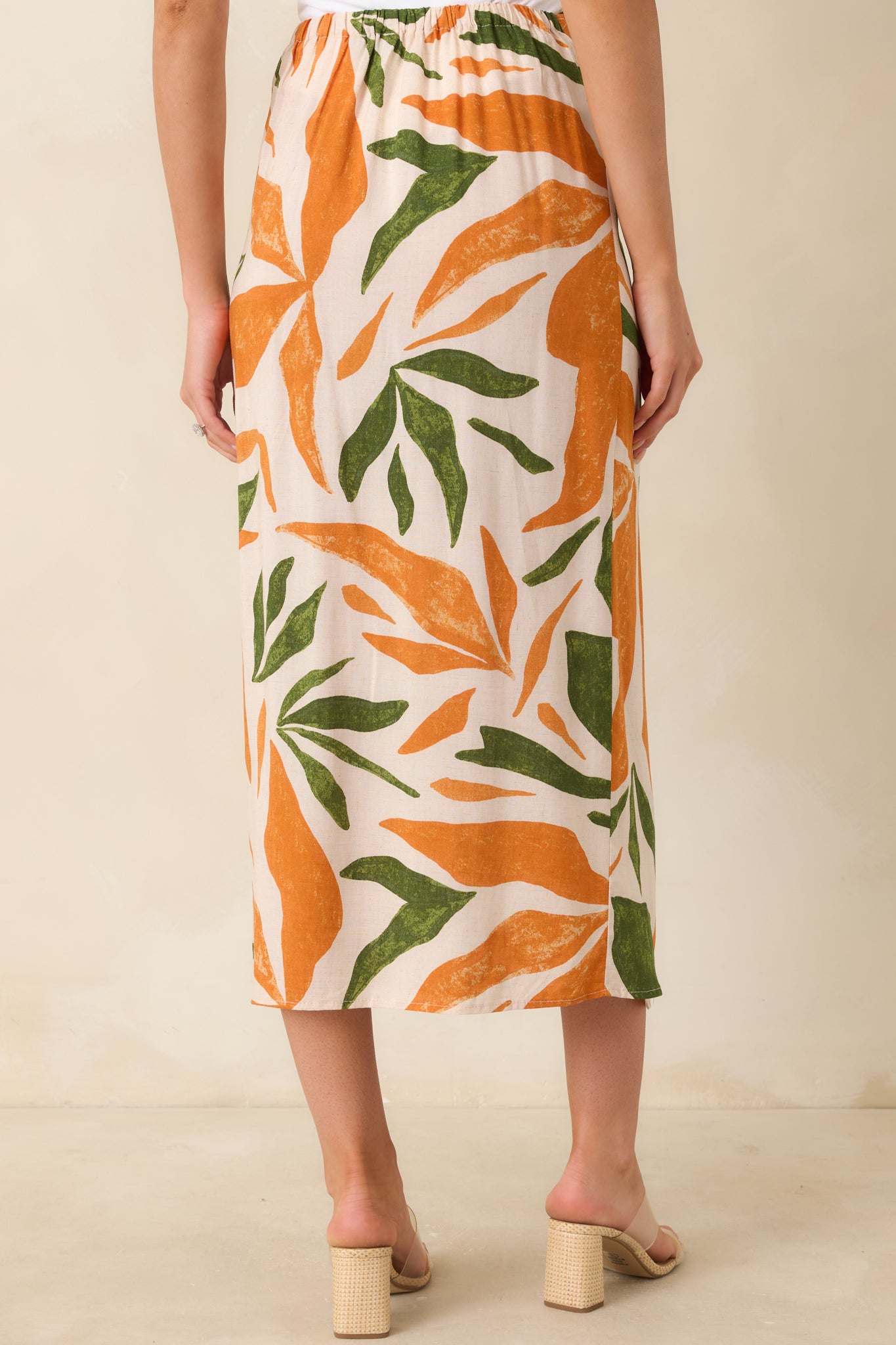 Tropical print midi skirt showcasing elastic waist insert and flowing rear silhouette.

