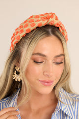Textured orange polka dots on a burlap colored headband with a knot at the top center.