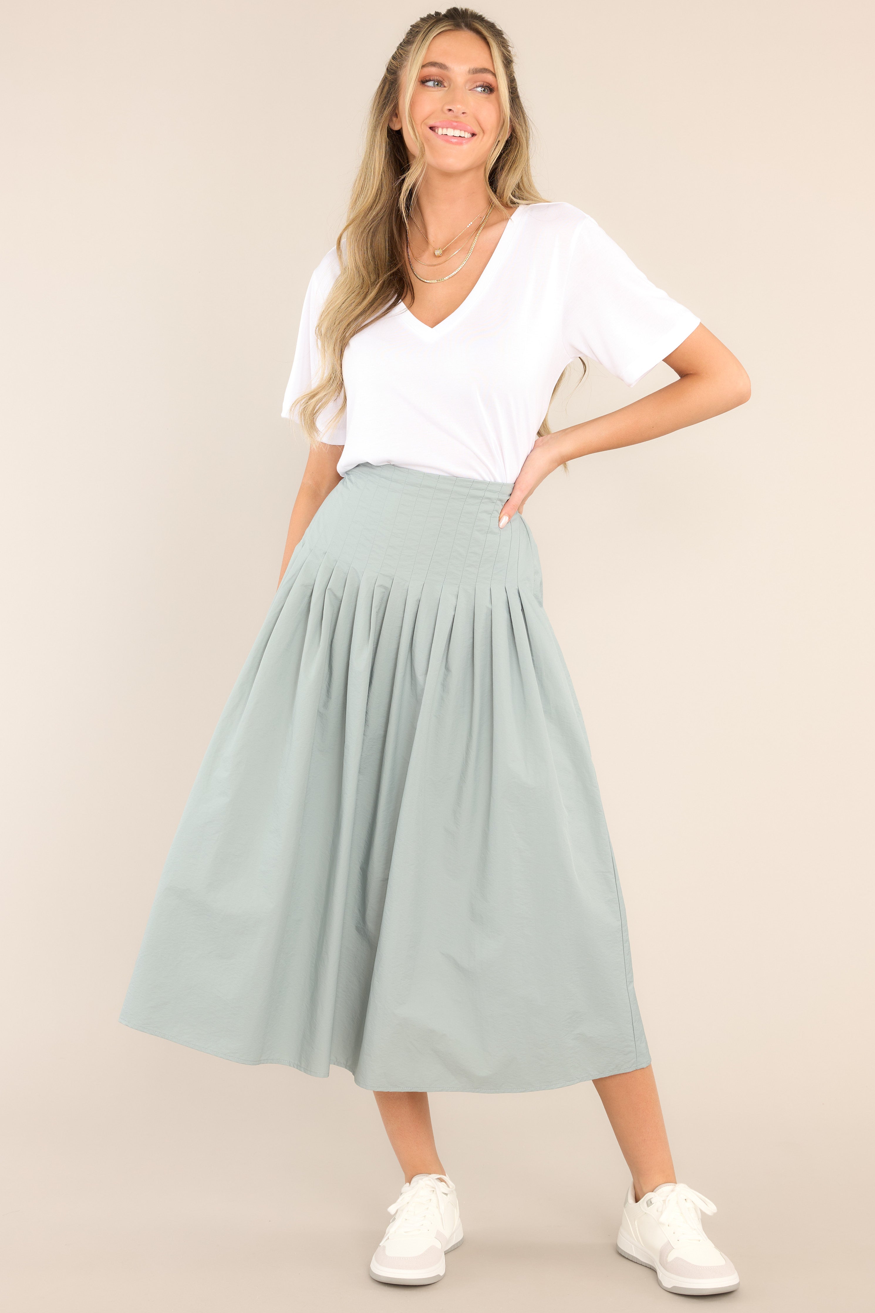 Full body view of this skirt that features a high waisted design, an elastic insert at the back of the waist, and intricate pleats around the hipline.