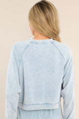 Back view of this sweatshirt that features a ribbed crew neckline, exposed seams, a washed design, ribbed cuffed long sleeves, and a cropped hemline.