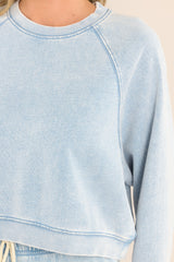 Close up view of this sweatshirt that features a ribbed crew neckline, exposed seams, a washed design, ribbed cuffed long sleeves, and a cropped hemline.