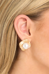 These gold and pearl earrings feature a textured diamond shaped stud, a large faux pearl, and secure post backings.