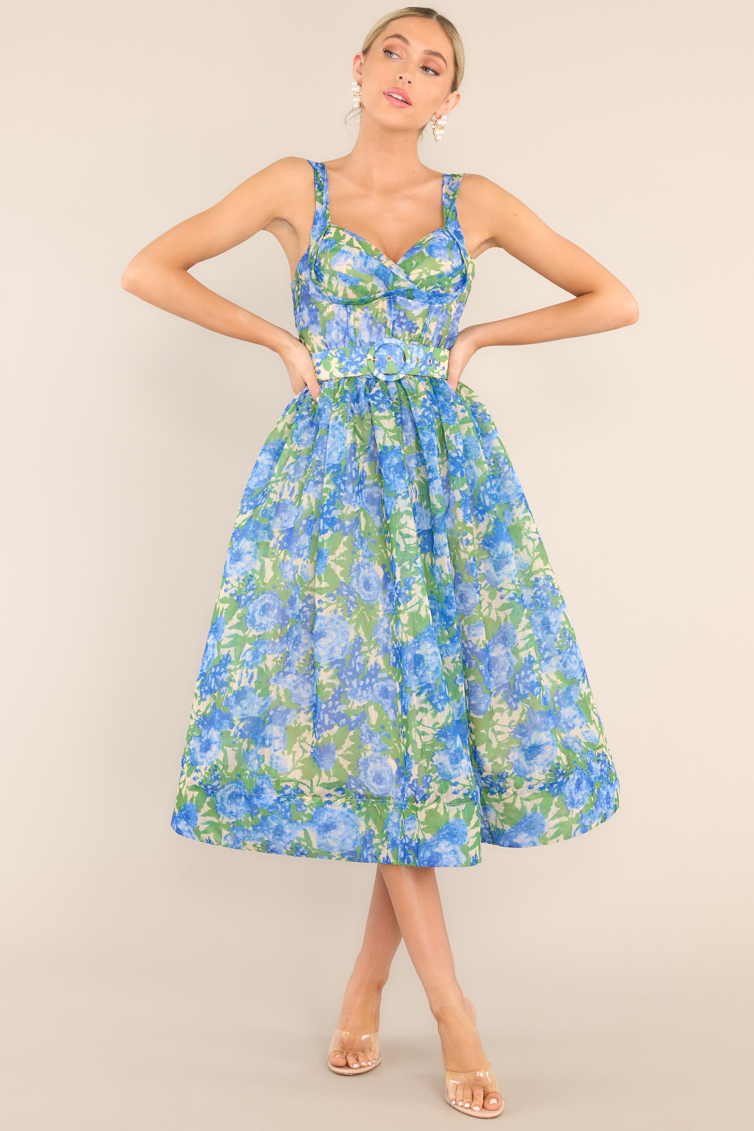 Full body view of this dress that features a sweetheart neckline, adjustable straps, a zipper down the back with a smocked insert, a padded bust, boning in the bodice, belt loops, an adjustable belt, and a thick hemline.