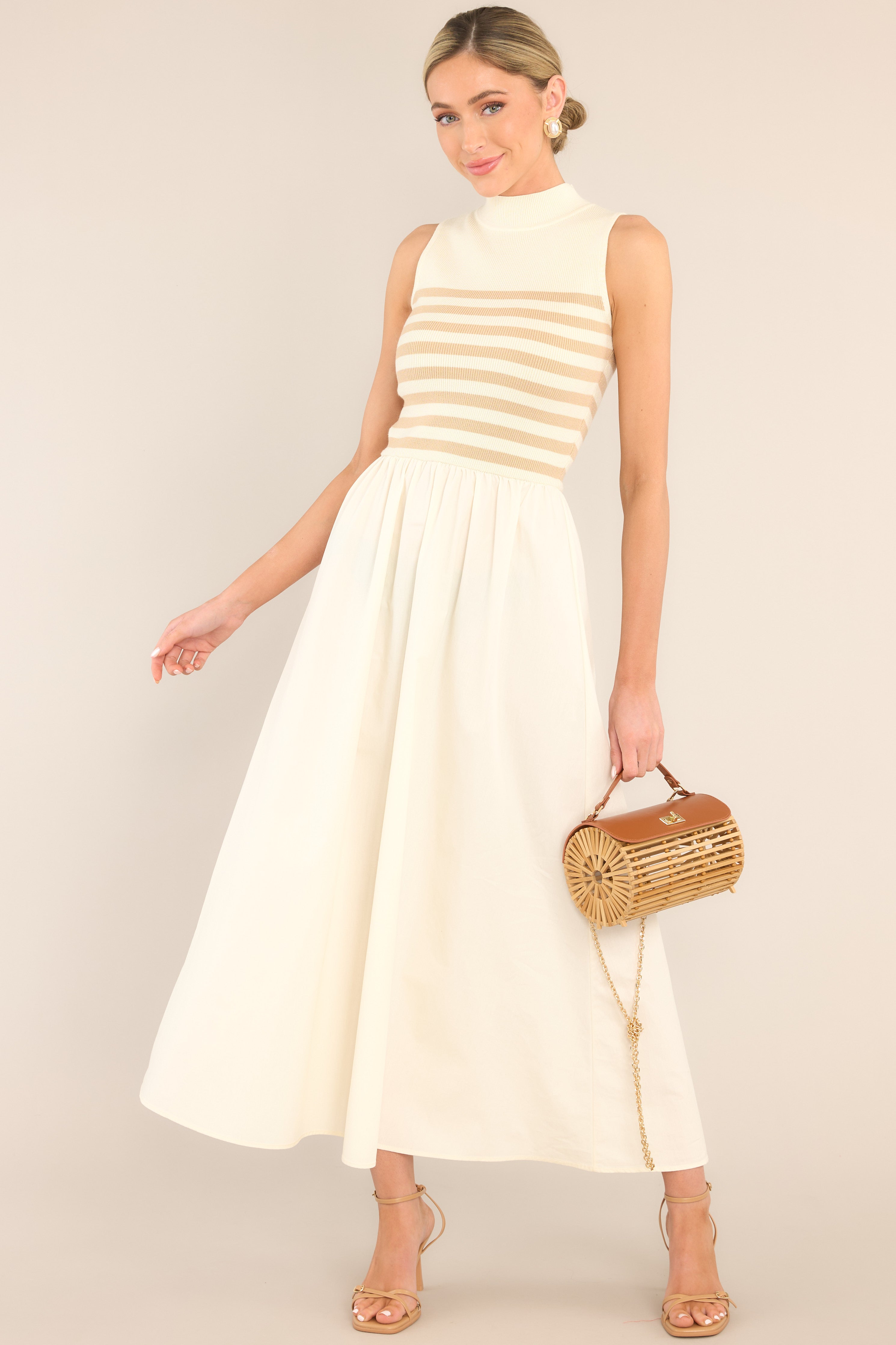 This tan and white dress features a high neckline, a striped sweater bodice, and a flowy skirt.