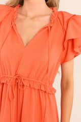 Close up view of this dress that features a v-neckline with a self-tie closure, ruffled flutter sleeves, a drawstring waistband, and a long, flowy skirt.