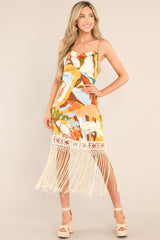 This multi-colored dress features a cowl neckline, thin adjustable cross straps, a colorful pattern, and fringe detailing.