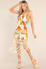 Front view of this dress that features a cowl neckline, thin adjustable cross straps, a colorful pattern, and fringe detailing.