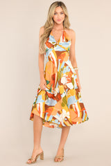Full body view of this dress that features a v-neckline, a self-tie feature at the back of the neck, an open back, a discrete back zipper, a twisted bust detail, and a colorful pattern.