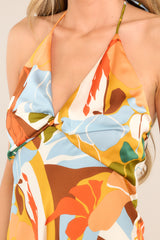 Close up view of this dress that features a v-neckline, a self-tie feature at the back of the neck, an open back, a discrete back zipper, a twisted bust detail, and a colorful pattern.