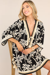 Front view of this cover up that features a v-neckline with a self-tie feature, crochet detailing, a self-tie belt, a split hemline with self-tie features, and wide sleeves with open knit detailing.